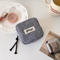 Detailed close-up of a quilted checkered pouch with hisocute label and woven rope zippers - Black