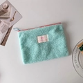 Close-up of mint green plush storage bag with Lucky gate label and colorful zippers - Green