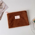 Close-up of brown plush cosmetic bag with pink bow logo and soft fuzzy texture details - Brown