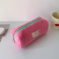 Dettaglio di un astuccio di peluche rosa con cerniera verde menta su una scrivania - Rosa Rossa