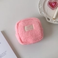 Flat lay of pink plush cosmetic bag with zipper on white tray and aesthetic props - Pink