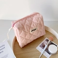 Detail of pink splash pattern quilted makeup bag with ribbon zipper and brand label - Pink Floral