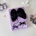 Detailed view of purple plush photo album cover featuring a large black bow and branding - Purple Cover