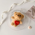 Macro view of plush brown teddy bear keychain with embroidered red heart and gold LOVE text - Brown