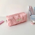 Close-up van roze gewatteerde etui met 3D-strikken en isocute stoffen label op bureau - Roze