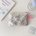 Detail of silver quilted pouch with bow texture, pink lanyard, and zipper closure - Butterfly Quilting / Silver
