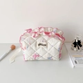 Nahaufnahme der gesteppten Kosmetiktasche mit Blumenmuster und rosa Rüschenrand - Weiß
