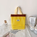 Detail of yellow mesh cosmetic bag with zipper and logo on a stylish vanity table - Yellow