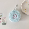 Close-up of light blue plush round coin purse with pink spiral embroidery and white clasp - Blue