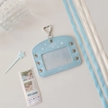 Macro detail of a light blue faux leather card holder with heart buckle and silver eyelets - Horizontal / Blue