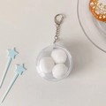 Detail der runden transparenten PVC-Tasche mit weißen Plüschbällen und silbernem Clip - Kleine Größe (58mm) Einzeltasche