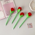 Flat lay of four artificial rose ballpoint pens with red velvet petals and green stems - Red Rose Style