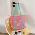 Bolso de malla rosa con asas verdes colgado en la puerta, ideal para playa o viaje - Rosa