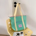 Detalle de bolsa de malla verde con correas amarillas y cremallera rosa en silla - Verde