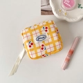 Flat lay of cherry plaid makeup bag with lipstick and beauty accessories on white - Yellow