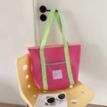 Detalle de una bolsa de malla rosa con asas verdes en una silla para la playa o compras - Rosa rojo