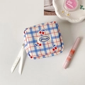 Detail view of cherry pattern plaid makeup bag with ribbon zipper on a styled white background - Blue