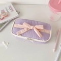 Close-up of purple stationery bag with pink fabric bow and dual ring zippers on desk - Purple