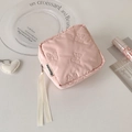 Close-up of pink quilted makeup bag with 3D bow patterns and white ribbon zipper pull - Pink