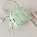 Detailed view of mint green quilted bow pattern cosmetic bag with ribbon zipper pulls - Green