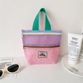 Dettaglio borsa a rete rosa e viola con doppia cerniera e manico verde intrecciato - Rosa
