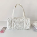 Detail of white quilted barrel bag featuring bow patterns and heart zipper pocket - White