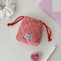 Detailed close-up of quilted red plaid drawstring bag with cherry print and HISOCUTE label - Red