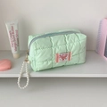 Dettaglio della pochette trapuntata verde chiaro con manico in perle e zip di chiusura - Verde