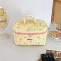 Détail d'une trousse à maquillage matelassée à carreaux jaunes avec nœud rose - Jaune