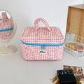 Détail de la trousse à maquillage matelassée à carreaux rouges avec nœuds bleus et zip - Rose rouge