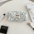 Close-up of quilted floral cosmetic bag with blue flower pattern and zipper ribbon detail - Blue Floral - Small