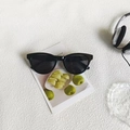 Occhiali da sole cat-eye neri classici con lenti scure su sfondo artistico moderno - Nero