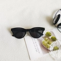 Classic retro black cat-eye sunglasses with dark round lenses on a textured white surface - Black