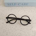 Nahaufnahme einer schwarzen runden Kinderbrille auf einer modernen Terrazzofläche - Schwarz
