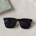 Minimalist wide-frame black sunglasses for men and women on a white textured background - Black