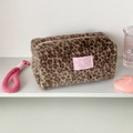 Close-up of plush leopard print makeup bag with pink zipper pull and brand patch - Brown