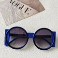 Oversized Klein Blue round sunglasses with gradient grey lenses on a Vogue magazine - Transparent Blue