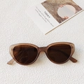Translucent amber cat-eye sunglasses with dark brown lenses on a textured white surface - Champagne