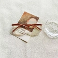 Montatura occhiali cat-eye con sfumatura marrone su elegante sfondo decorativo - Cachi