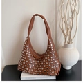 Detalle de bolso hobo marrón con tachuelas plateadas sobre cuero sobre un libro - Marrón