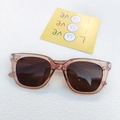 Braune transparente Sonnenbrille mit dunklen UV-Gläsern auf weißer strukturierter Fläche - Champagner