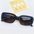 Classic black rectangular sunglasses with brown lenses on a decorative background - Dark Brown