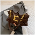 Detail van donkerbruine cloud bag met een grote gouden vierkante gesp en ketting - Bruin