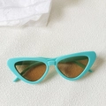 Close-up of mint green cat-eye sunglasses with brown lenses on a white textured surface - Mint Green Frame Brown Lens