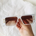 Close-up of white rectangular sunglasses with brown lenses and golden B logo details - White
