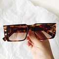Macro view of tortoise square sunglasses featuring gold B logo and gradient brown lenses - Tortoiseshell