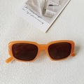 Détail de lunettes de soleil carrées orange rétro avec rivets métalliques sur fond blanc - Orange Gelée