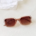 Macro shot of stylish square translucent tea-colored sunglasses with gradient brown lenses - Champagne