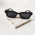 Classic black rectangular sunglasses with thick frames on a beige stone surface - Perforated Style