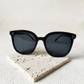 Lunettes de soleil noires surdimensionnées avec clous à trois points sur socle en pierre - Trois points